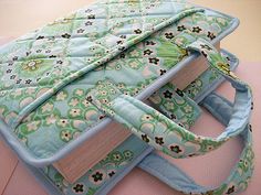 a green and blue bag with flowers on it sitting on top of a pink surface