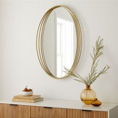 an oval mirror hangs on the wall above a dresser