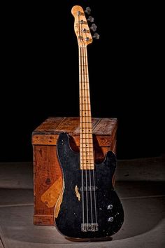 a black bass guitar sitting on top of a wooden box