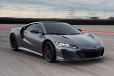 a gray sports car driving down a race track with motion blurs in the background