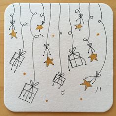 a white coaster with gold stars and presents hanging from the strings on it's side