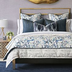 a bed with blue and white comforter in a bedroom next to a wall mounted gold leaf