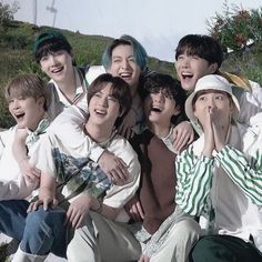 a group of young men sitting next to each other on top of a grass covered field