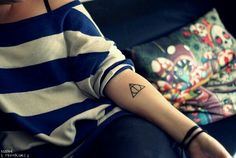 a woman with a small triangle tattoo on her arm sitting in front of a pillow