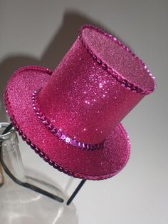 a pink hat sitting on top of a glass bottle