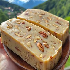 two pieces of cheese sitting on top of a wooden plate with pecans in the background