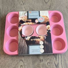 a pink muffin tray with cupcakes in it on top of a wooden table