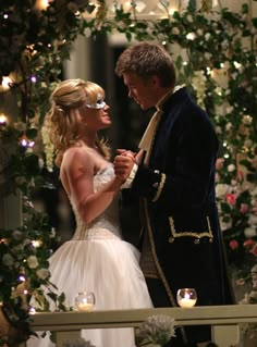 a man and woman standing next to each other in front of a wedding arch with candles