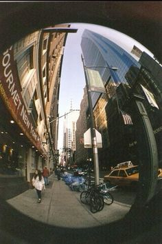 the reflection of people walking down the street in front of tall buildings