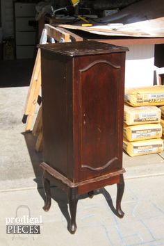 an old wooden cabinet sitting on top of a cement floor next to stacks of boxes