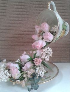 a vase with flowers in it sitting on a table next to a cup and saucer