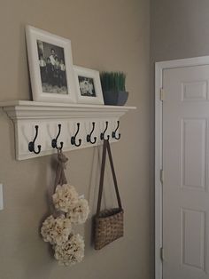 there is a coat rack with hooks and flowers on the wall next to two pictures