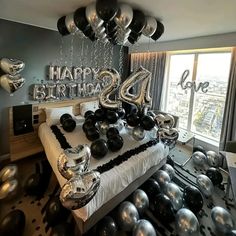 a bedroom decorated with balloons and black and silver decorations for a birthday party or celebration