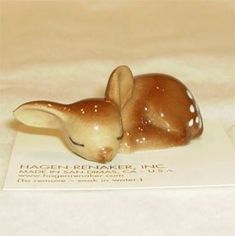 a small figurine of a baby deer laying on top of a white sheet