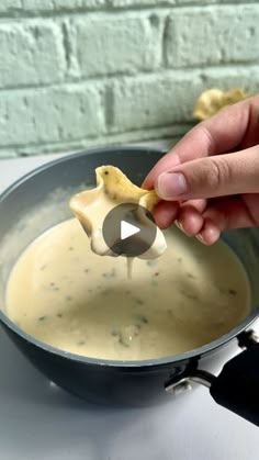 a person dipping some food into a pan