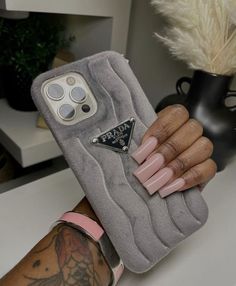 a woman's hand holding a phone case with pink nails and a ring on it