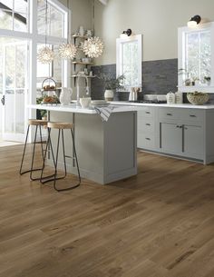 a large kitchen with wooden floors and white cabinets