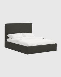 a bed with white sheets and black headboard