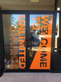 an orange and black sign is on the front door of a building that has glass doors