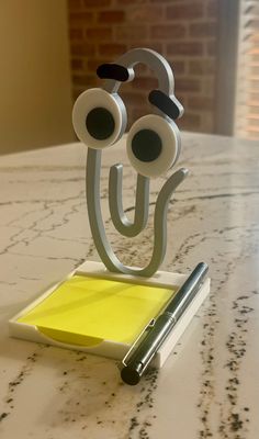 a pen and paper holder with eyeballs on it sitting on top of a table