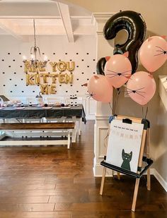 balloons are in the shape of animals and cats on easel next to a sign that says, we're you kitten me