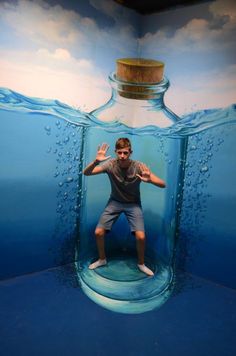 a man is standing in front of a bottle with water inside and his arms are stretched out