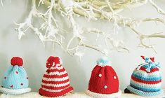 five knitted hats sitting on top of a shelf next to a branch with white branches in the background