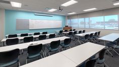 an empty classroom with desks and chairs in front of a large white board on the wall