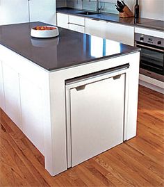 a bowl of fruit is sitting on the counter in this modern style kitchen with white cabinets and stainless steel appliances