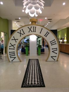 a large clock in the middle of a lobby with black and white tiles on the floor