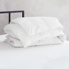 a bed with white sheets and pillows stacked on top of each other