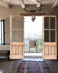 an open door leading to a balcony with a chair on the floor and a rug in front of it