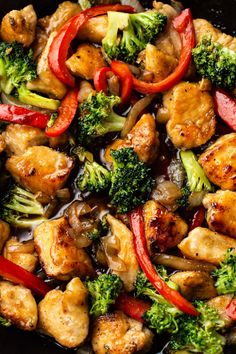 chicken and broccoli stir fry in a skillet with red peppers, bell peppers, and onions