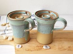 two coffee mugs sitting on top of a wooden table