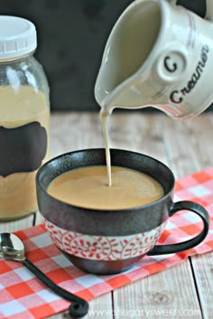 coffee being poured into a cup on top of a red and white checkered table cloth