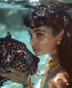 a woman is holding a leopard in her hands under the water's surface, while wearing gold jewelry