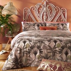 a bed with an ornate headboard and pillows in a room filled with potted plants