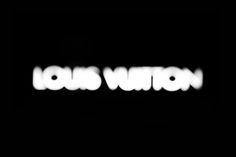 the word louis vuon is lit up in the dark with white letters on it