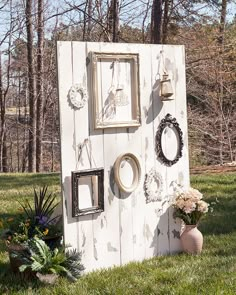 an old door is decorated with pictures and flowers on the grass in front of some trees