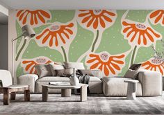 a living room with an orange and green flower wall mural on the wall next to two white chairs