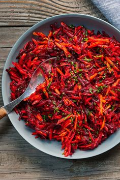 a white bowl filled with red food on top of a wooden table