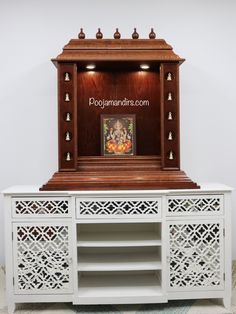 a white cabinet with carvings on the doors and drawers is shown in front of a wall