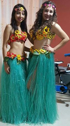 two women dressed in green grass skirts and flower headbands standing next to each other