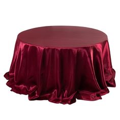 a round table covered with a red satin tablecloth and ruffles on top