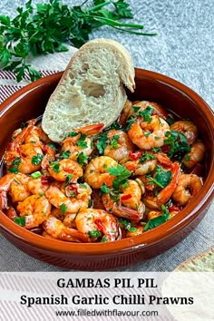 a bowl filled with shrimp and bread next to a piece of bread on top of a table