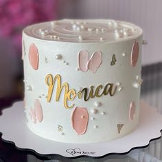 there is a white cake with pink and gold decorations on the top that says monica