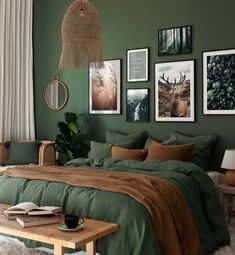 a bedroom with green walls and pictures on the wall above the bed, along with a coffee table