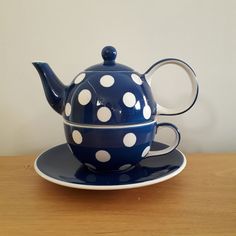 a polka dot tea pot and saucer on a wooden table