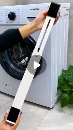 someone is holding up a phone in front of a washing machine with the door open