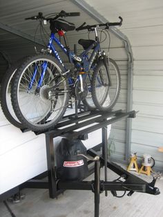 two bikes are parked on top of a bike rack in a garage with tools nearby